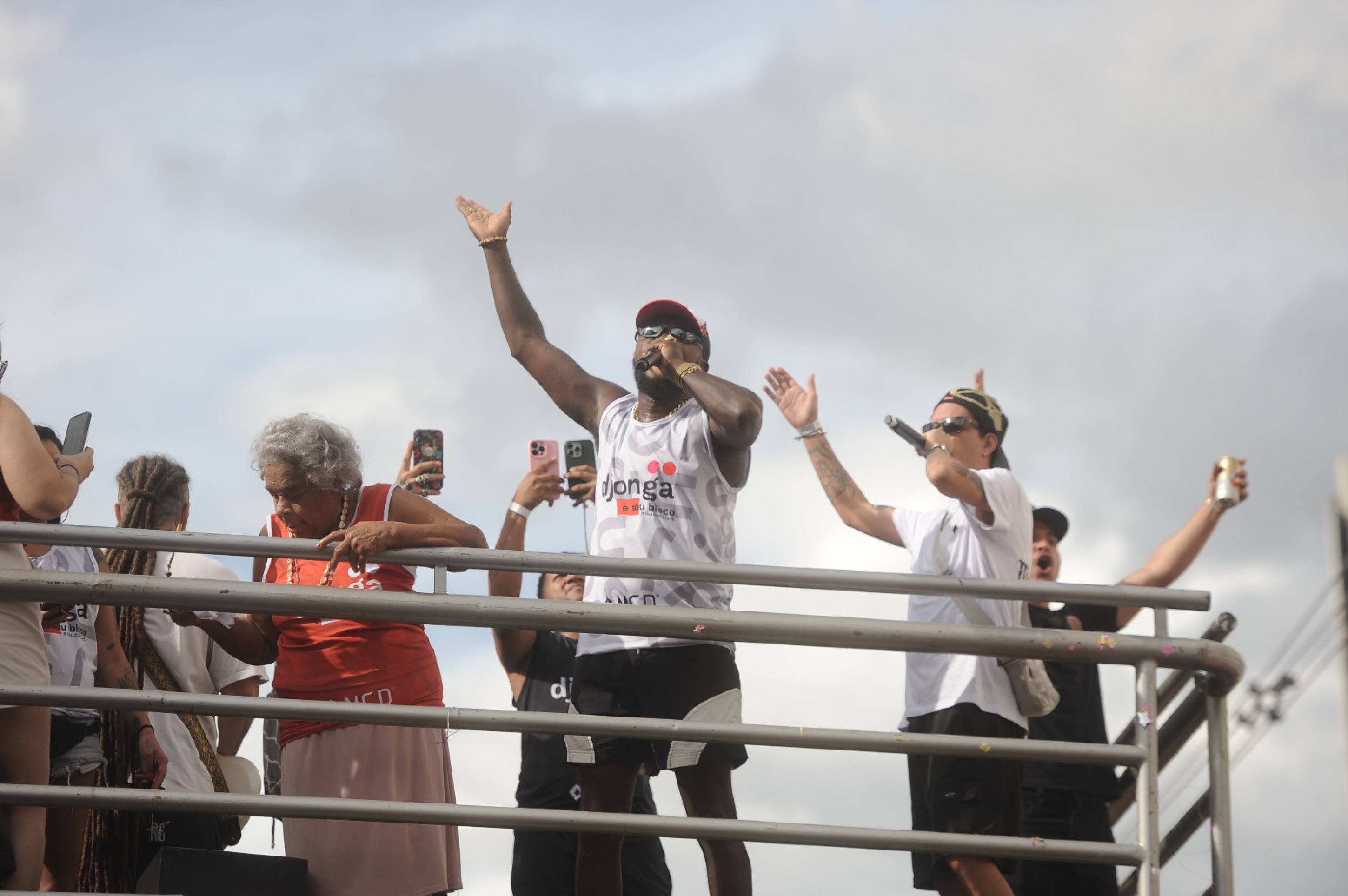 Ao lado de Djonga, de blusa vermelha, está dona Maria Eni, avó do rapper. Depois de levar a vovó para o palco em vários shows, Djonga apresenta dona Maria Eni à multidão de foliões em seu trio elétrico, que movimentou o sábado de carnaval em BH-Túlio Santos/EM/D.A Press