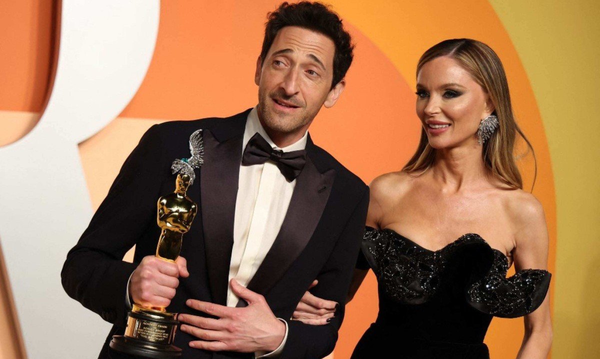 Adrien Brody segura a estatueta do Oscar, ao lado da esposa, atriz britânica Georgina Chapman -  (crédito: Michael Tran / AFP)