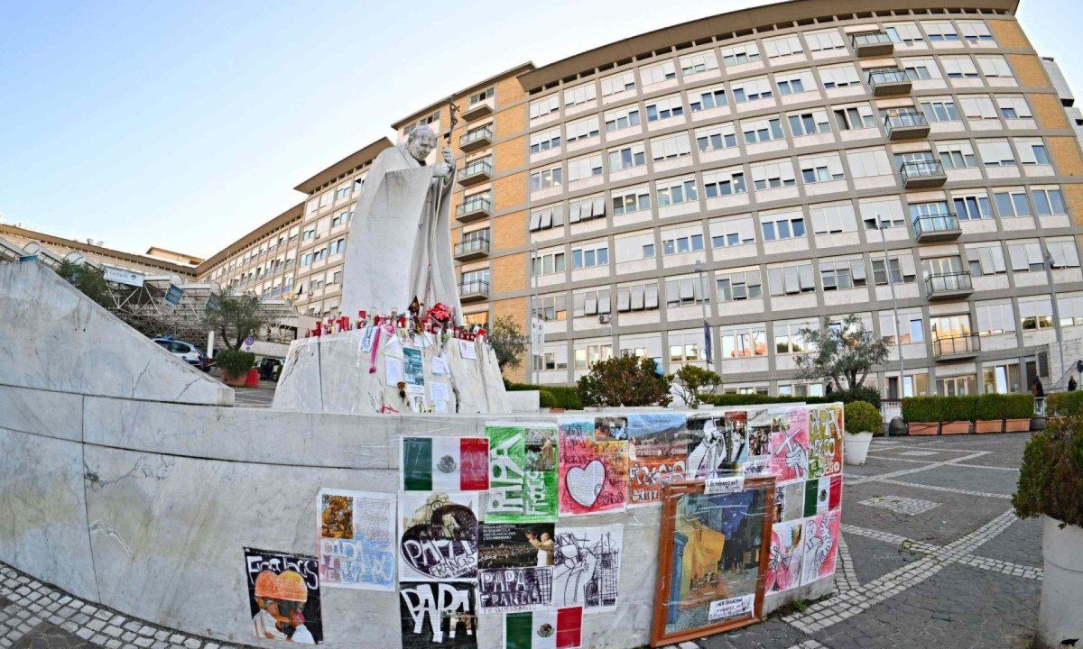 Cartazes e mensagens para o Papa Francisco são colados perto da estátua de João Paulo II, fora do Hospital Universitário Gemelli, onde o Papa Francisco está hospitalizado com pneumonia -  (crédito: Andreas SOLARO / AFP)