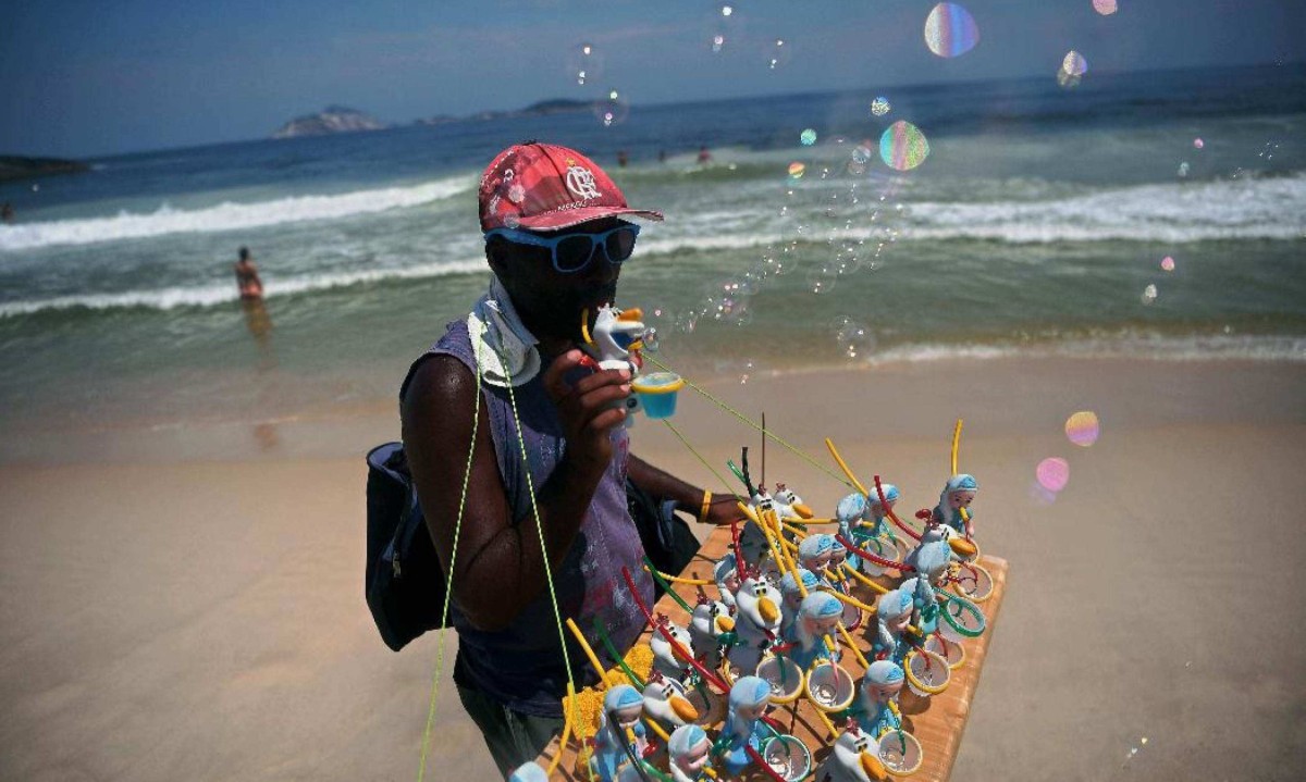 Vendedor ambulante na Praia de Leme durante semana com alerta de calor extremo   -  (crédito: Carl de Souza/AFP)