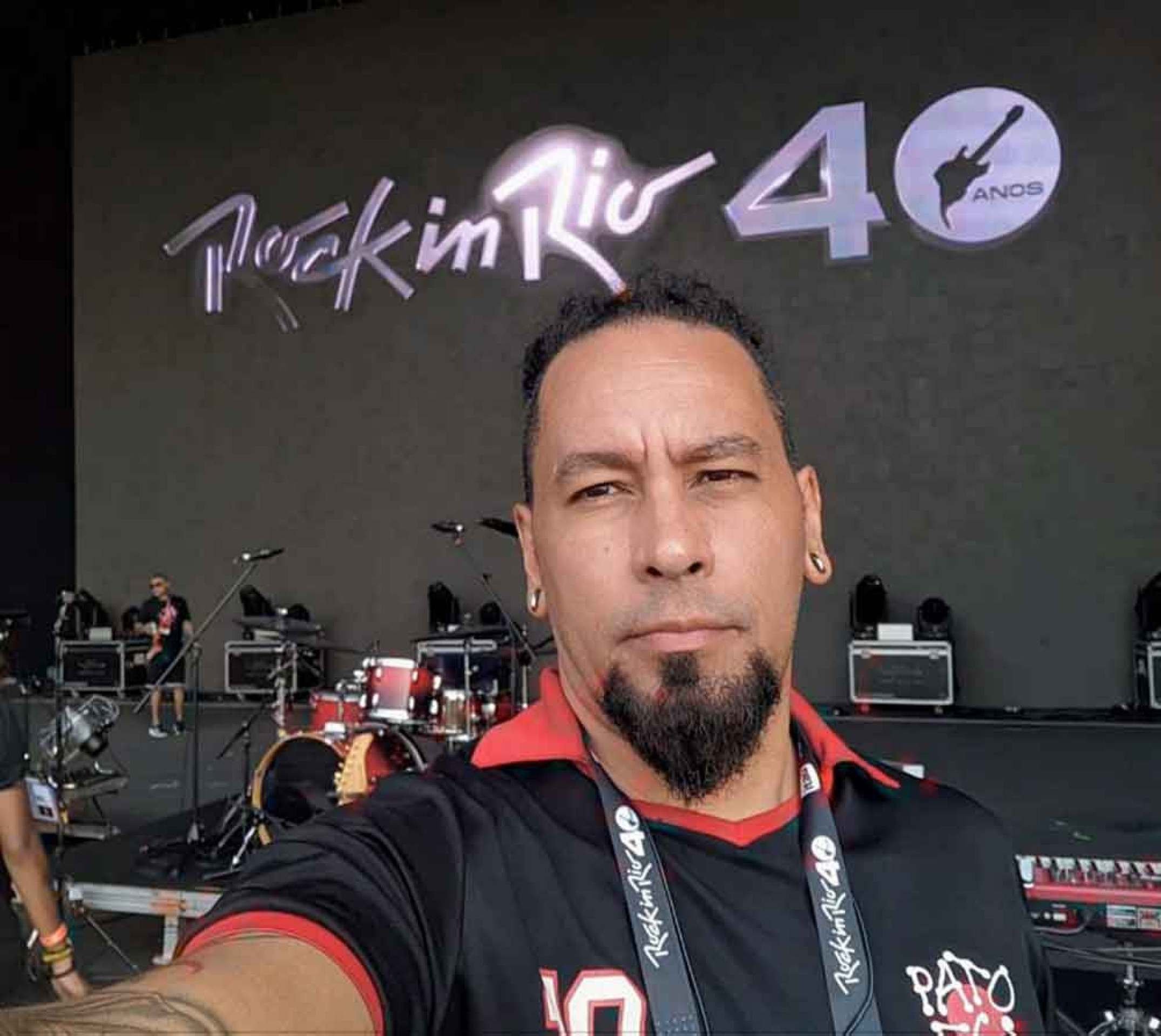 Raffa Fonseca olha para a câmera, atrás está o palco do Rock in Rio