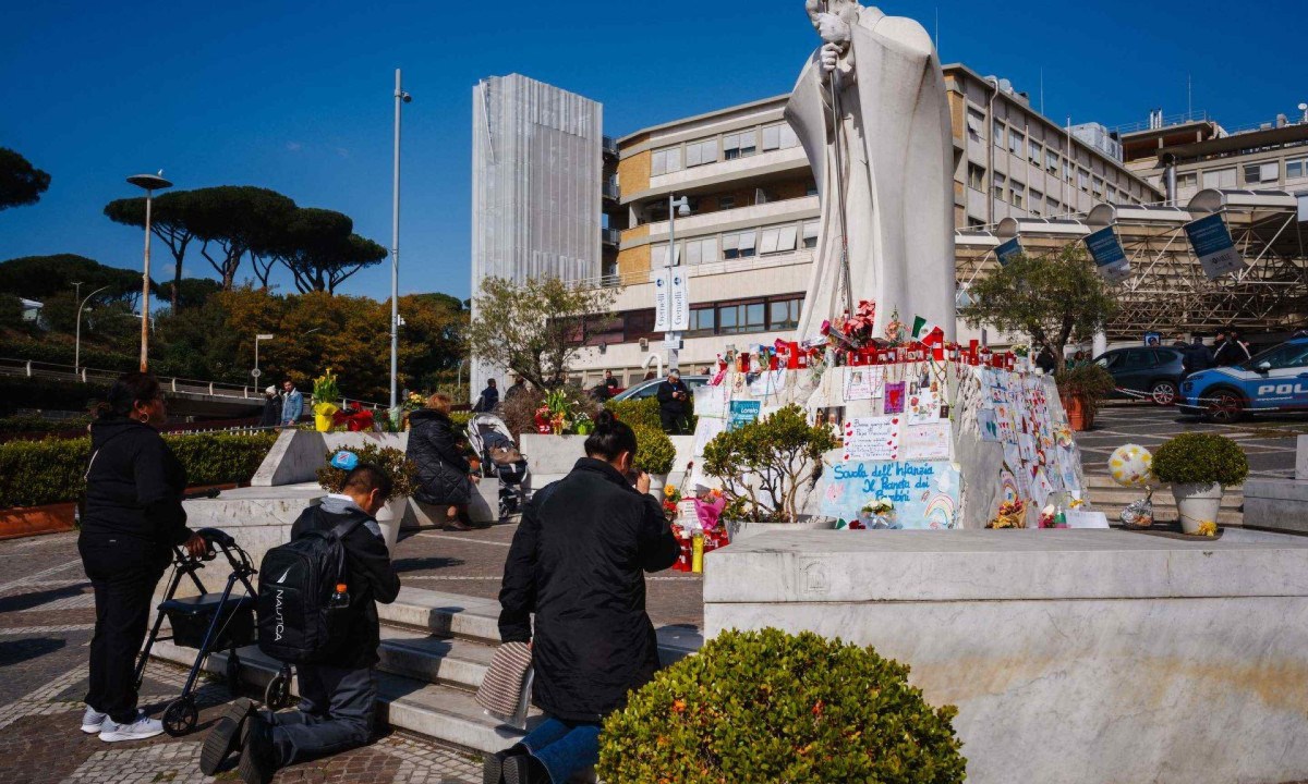  Fieis católicos rezam pela saúde do papa em estátua em frente ao Hospital Gemelli, de Roma, onde Francisco está internado há 3 semanas -  (crédito: DIMITAR DILKOFF/AFP)
