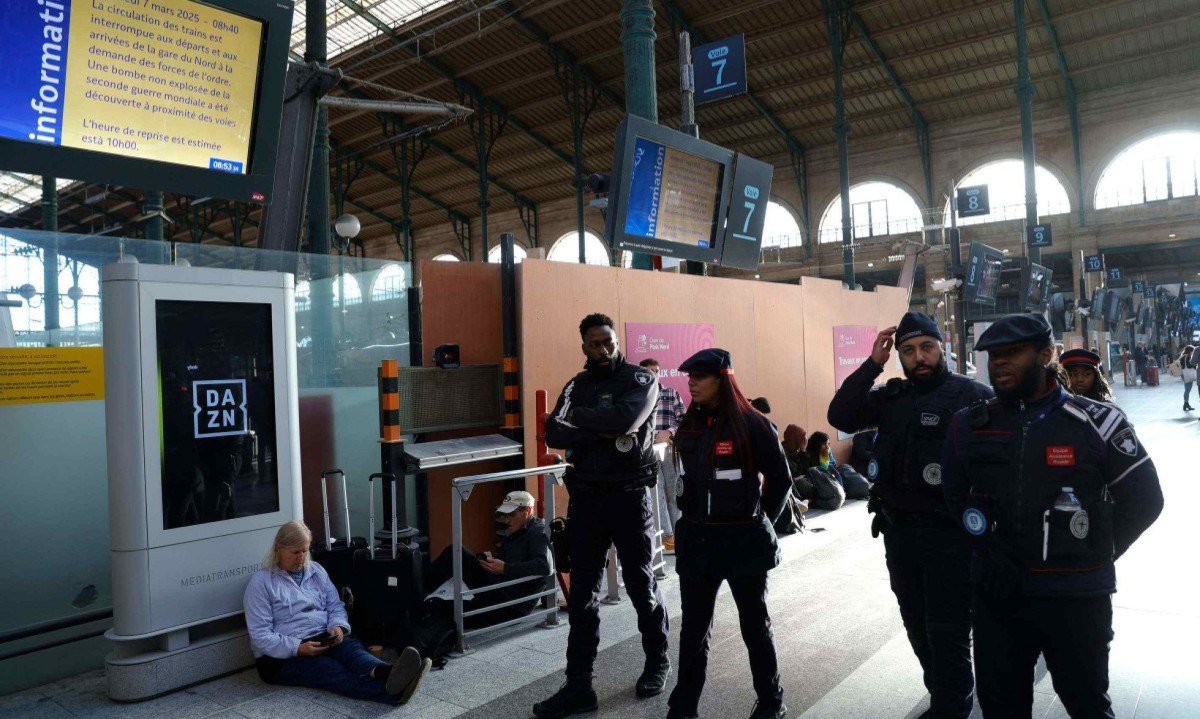  Guardas fardados andam pela Gare du Nord, em Paris, onde foi descoberta uma bomba da Segunda Guerra Mundial, enquanto passageiros esperam sentados pela volta dos trens