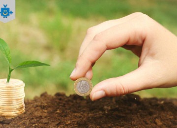 A imagem simboliza crescimento financeiro, mostrando uma mão colocando uma moeda na terra e uma pilha de moedas com uma planta crescendo sobre elas. Representa a ideia de que investir com planejamento gera retornos ao longo do tempo. O logotipo 