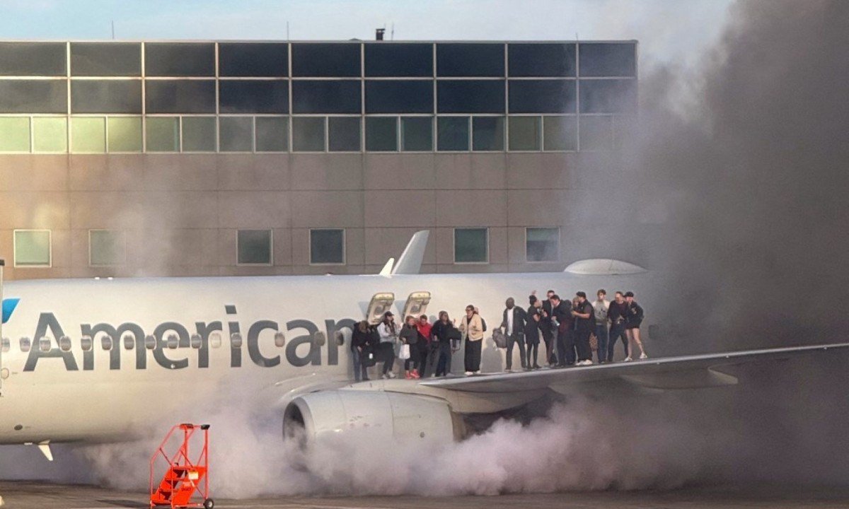 Passageiros ficaram em p&eacute; na asa do avi&atilde;o da American Airlines enquanto eram evacuados por causa do inc&ecirc;ndio at&eacute; uma ala do Aeroporto Internacional de Denver, no Colorado (EUA) -  (crédito: Branden Williams / Courtesy of Branden Williams / AFP)