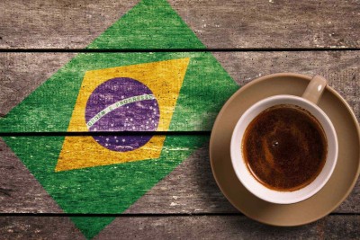 Xícara de café sobre mesa de madeira com bandeira do Brasil pintada; imagem meramente ilustrativa -  (crédito:  depositphotos.com /goglik83)