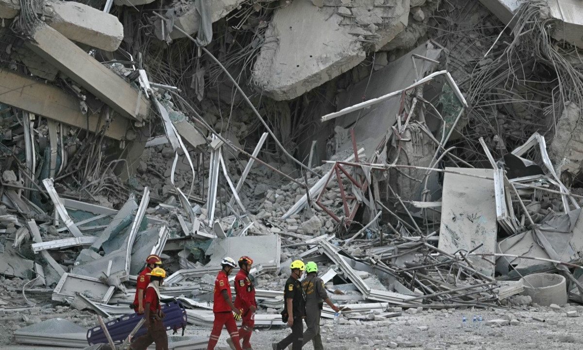 Equipes de resgate passam pelos destroços de um canteiro de obras de um prédio que desabar em Bangkok em 28 de março de 2025, por causa de um terremoto
