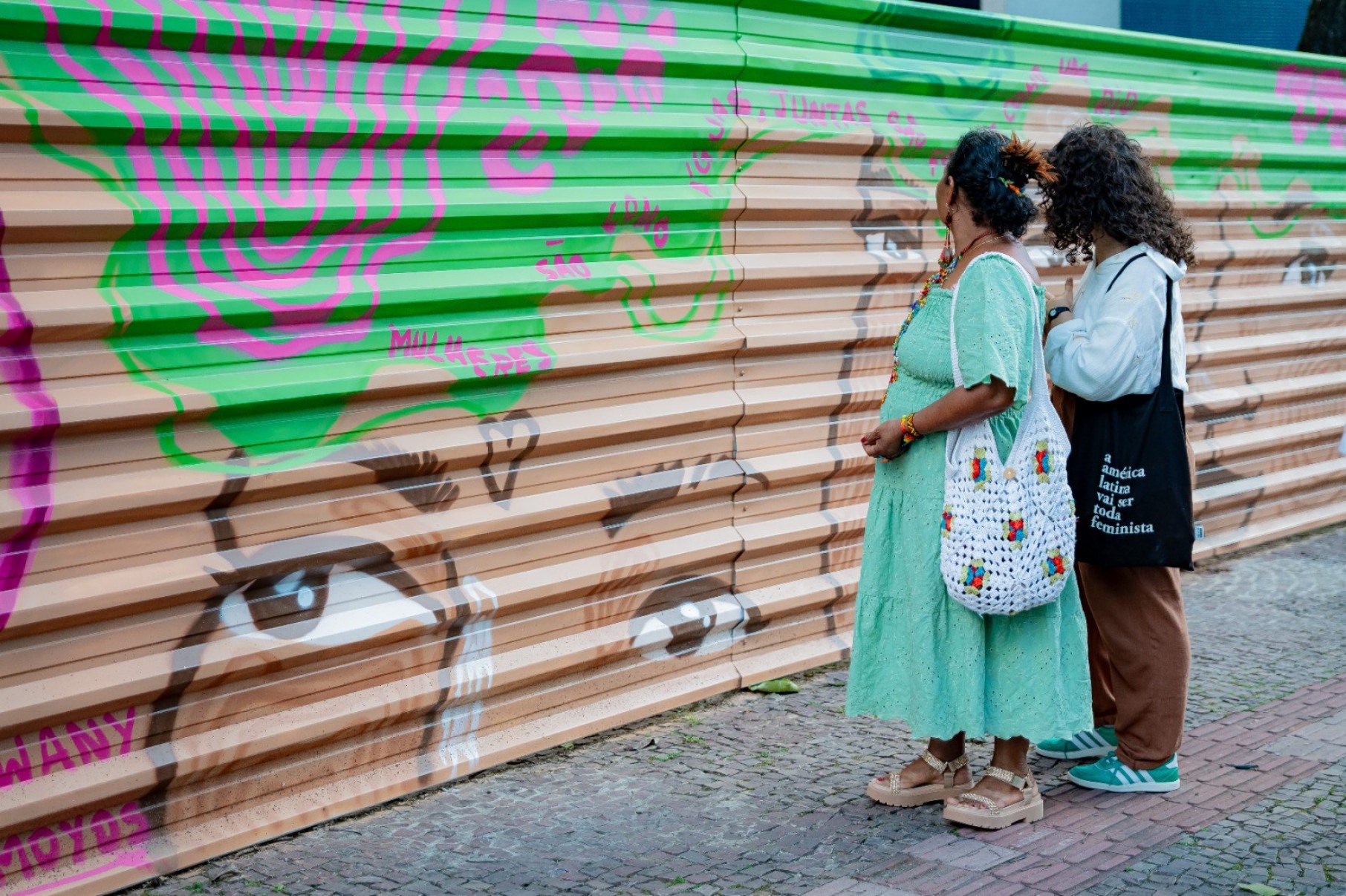 Os tapumes que cercam a área viraram tela para as artistas indígenas Liça Pataxoop e Kawany Tamoyos