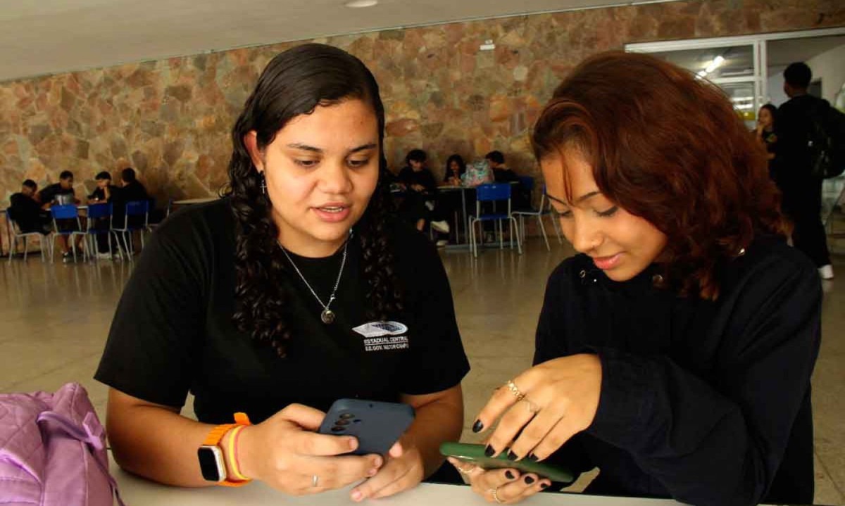 Alunas do ensino médio, Camily e Giovana checam mensagens no horário de almoço: As duas dizem estar mais atentas em sala, mas contam que elevaram o tempo na tela em casa -  (crédito: Jair Amaral/EM/D.A Press)