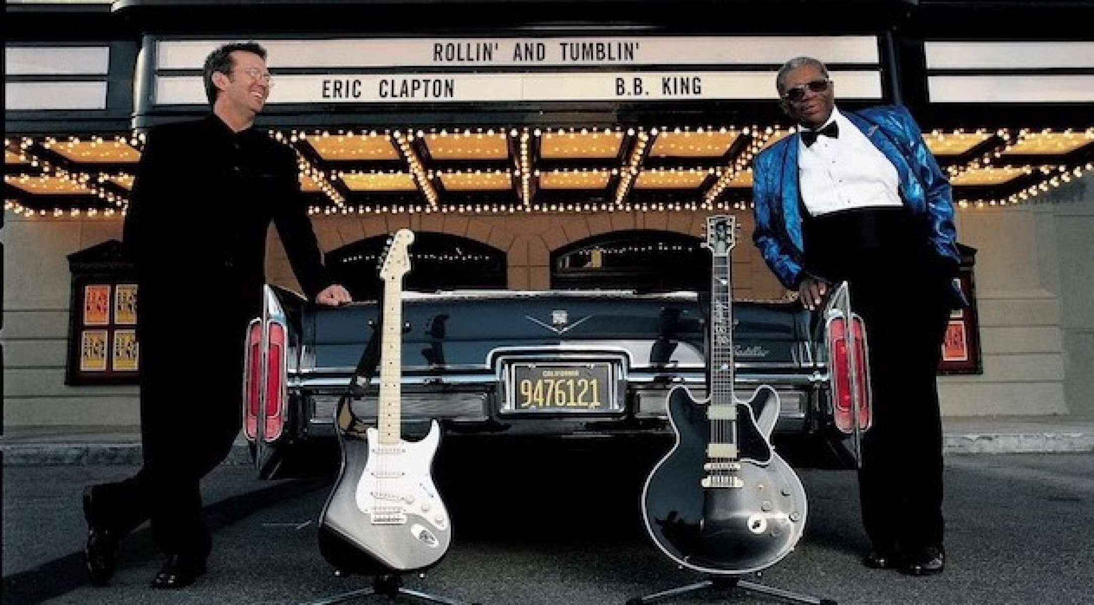 Eric Clapton e B.B King sorriem diante da fachada de um teatro, cujo letreiro traz os nomes da dupla