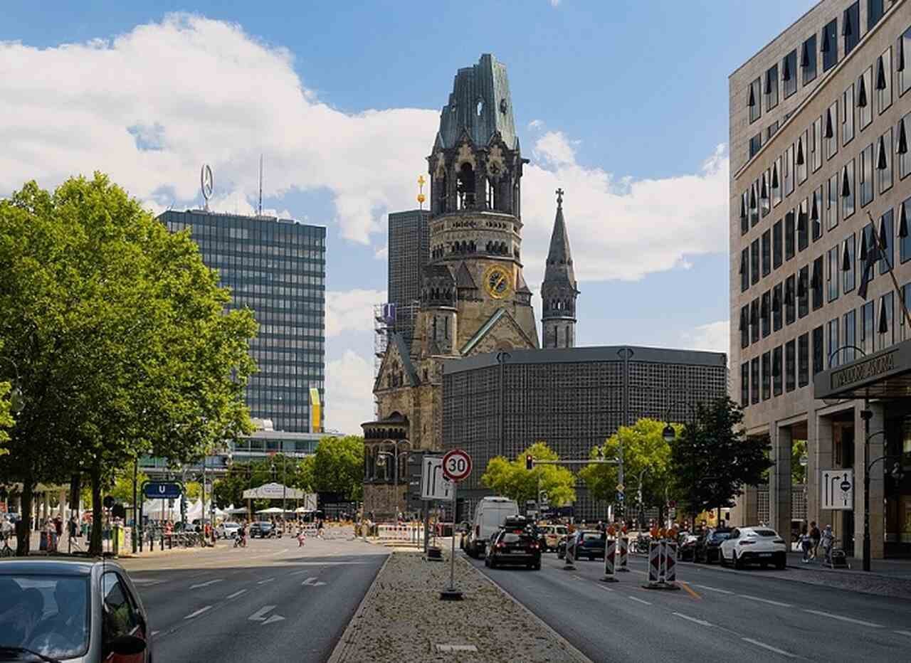 Igreja Kaiser Wilhelm (Kaiser-Wilhelm-Gedächtniskirche) - Descrição: Esta igreja foi bombardeada durante a Segunda Guerra Mundial e suas ruínas foram mantidas como um memorial. Ao lado, há uma moderna torre construída nos anos 1960 - Localização: Breitscheidplatz - Referências Históricas: O contraste entre as ruínas e a nova torre simboliza a destruição e a reconstrução de Berlim