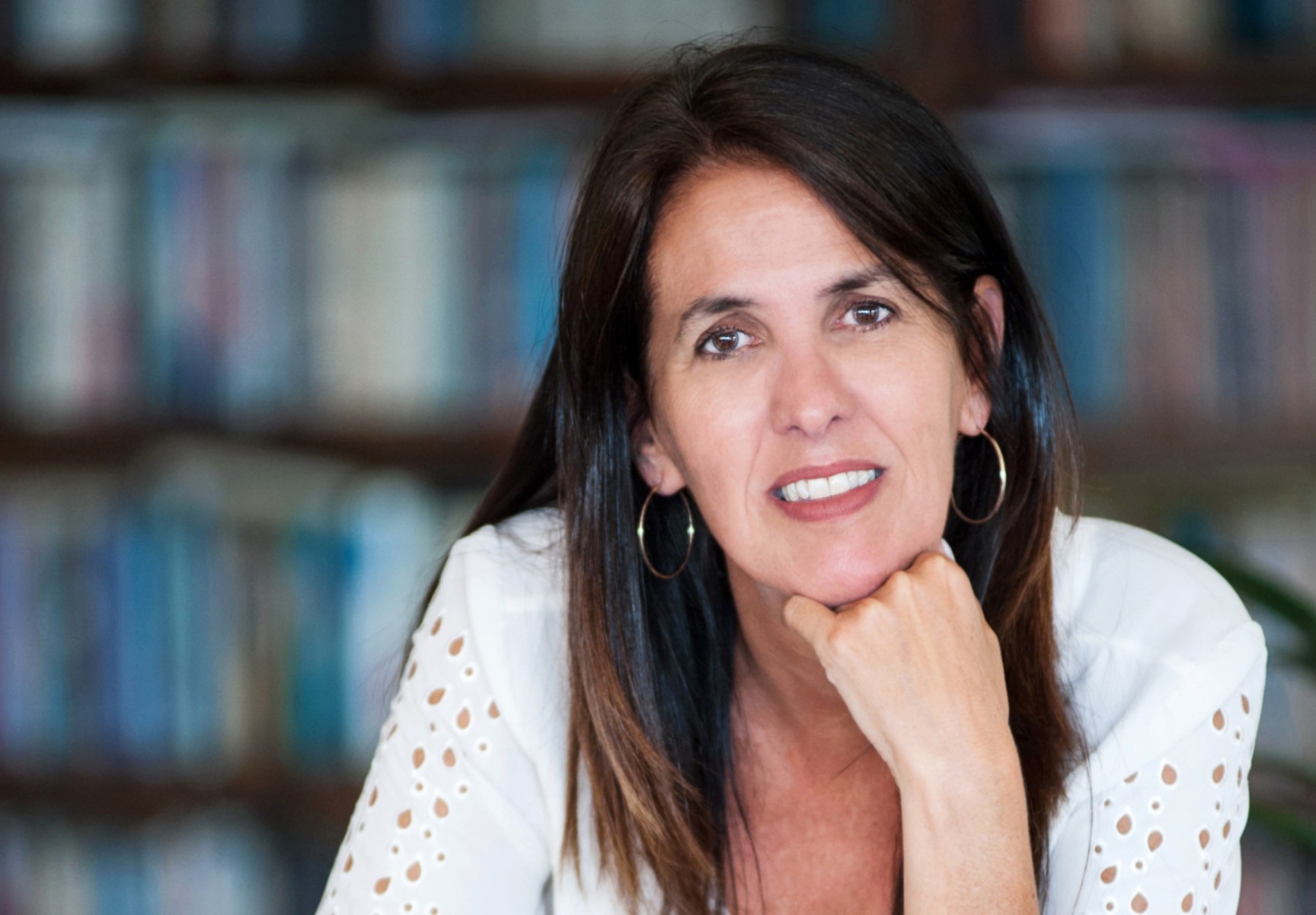 Com a mão no queixo, a escritora Martha Medeiros sorri e olha para a câmera