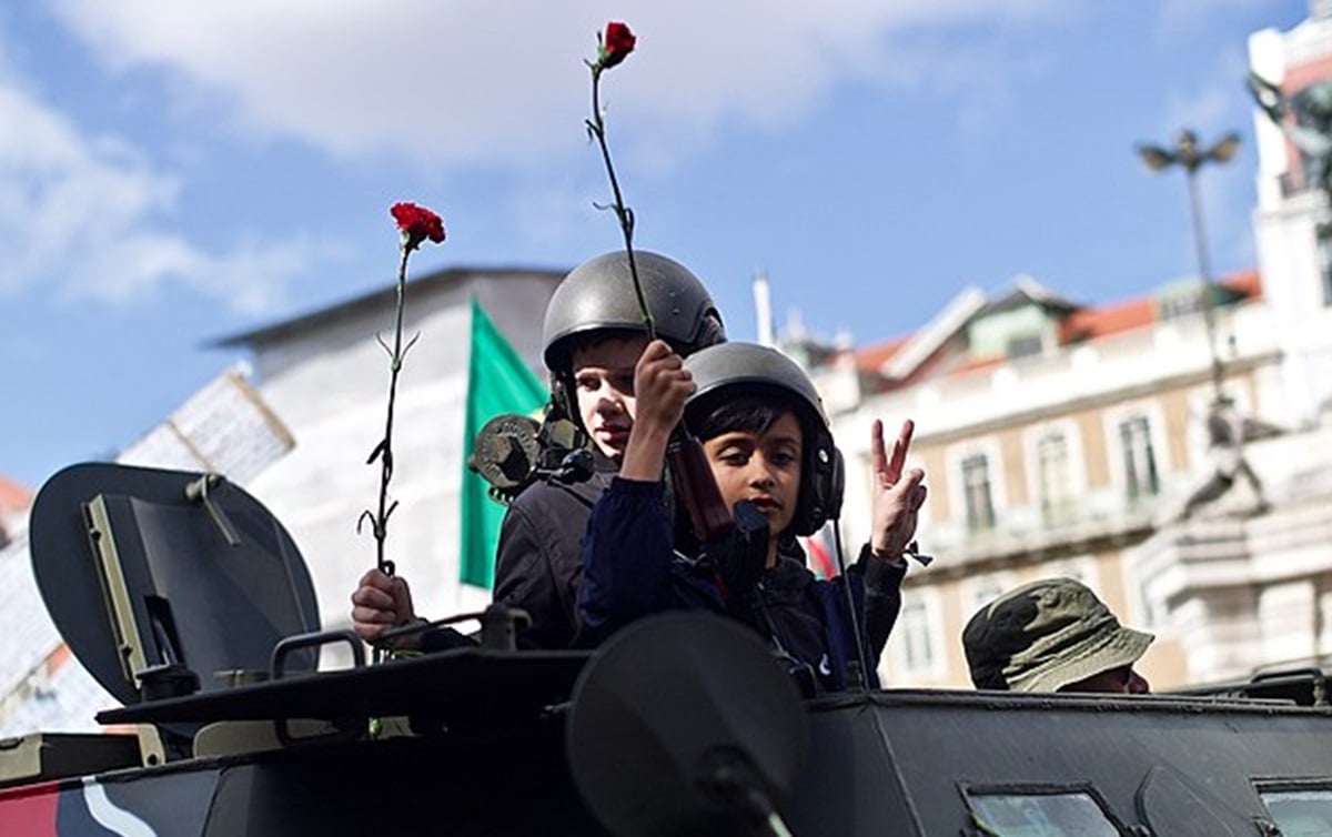 O nome Revolução dos Cravos se popularizou porque os soldados do exército português que derrubaram o regime de Salazar receberam cravos vermelhos e colocaram no cano de suas armas, desfilando pelas ruas. Até hoje, o gesto é repetido nas celebrações.-Pedro Ribeiro Simões/Wikimedia Commons
