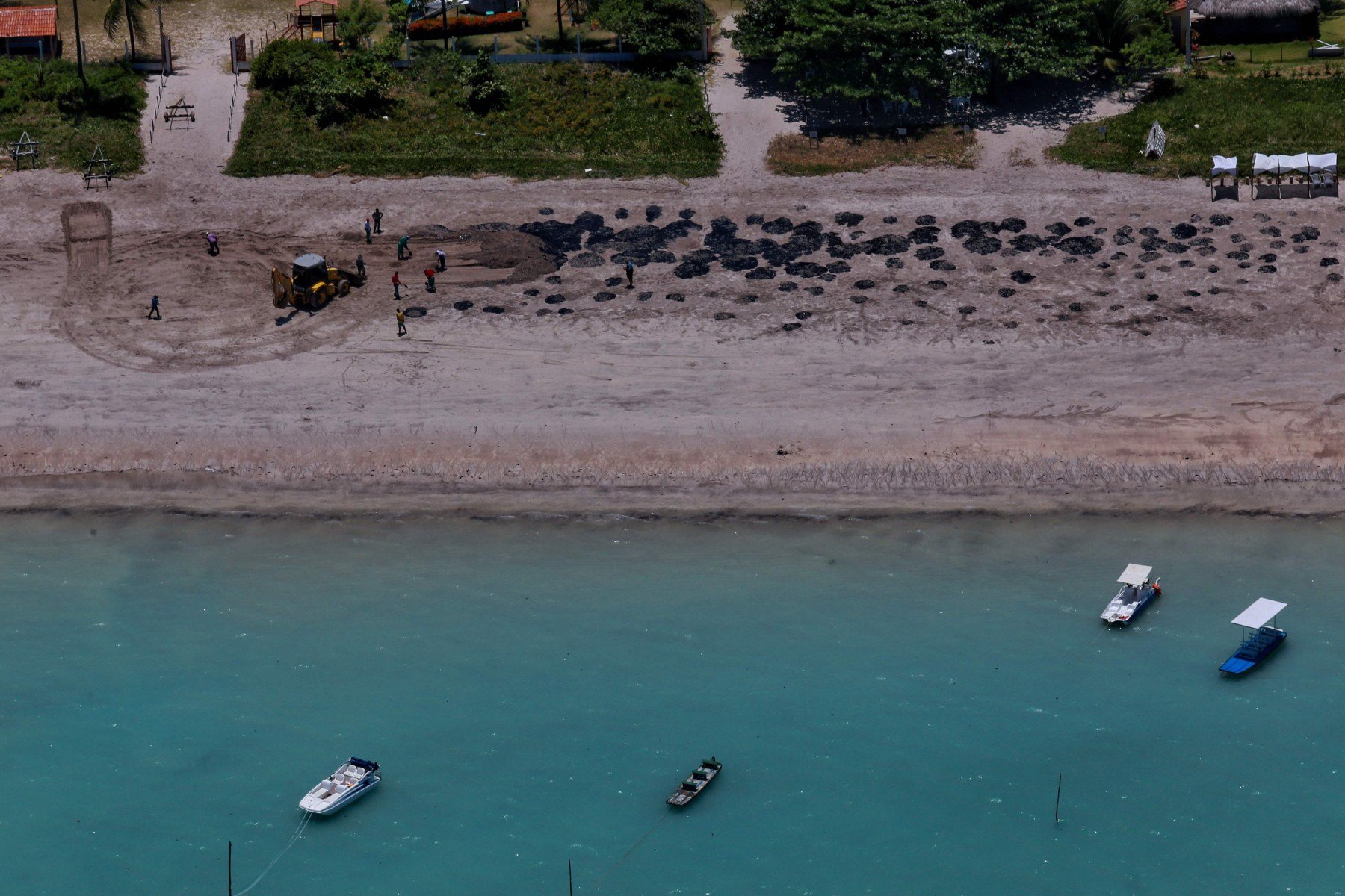  TOPSHOT - Handout picture released by Pernambuco State Government showing workers removing  oil spilled on Peroba beach, located at the city of Maragogi, Alagoas state, Brazil, on October 17, 2019.  Large blobs of oil staining more than 130 beaches in northeastern Brazil began appearing in early September and have now turned up along a 2,000km stretch of the Atlantic coastline. The source of the patches remain a mystery despite President Jair Bolsonaro's assertions they came from outside the country and were possibly the work of criminals. - RESTRICTED TO EDITORIAL USE - MANDATORY CREDIT 