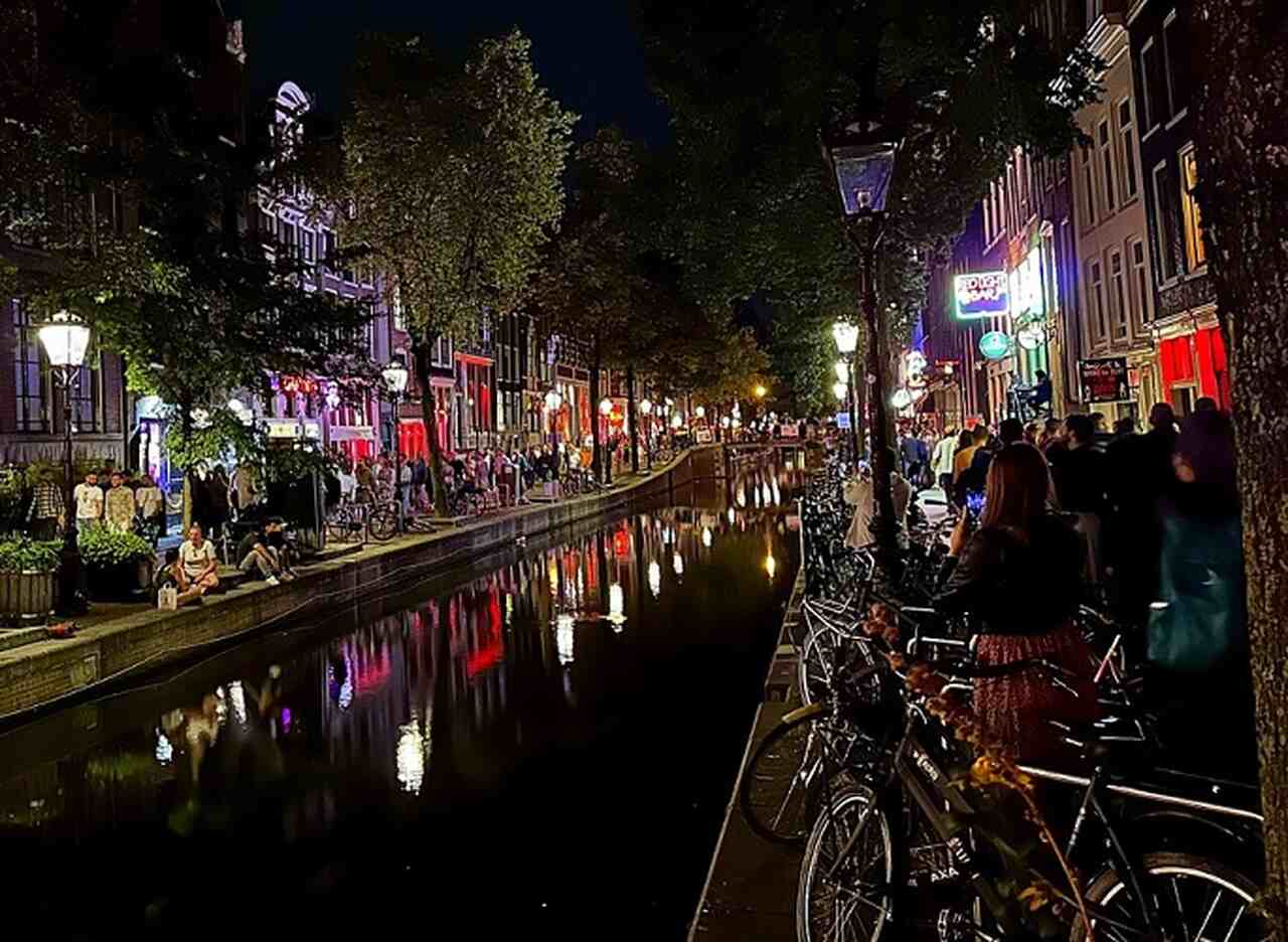 Red Light District (De Wallen) - Descrição: O bairro mais famoso de Amsterdã, conhecido por suas vitrines iluminadas em vermelho, tem uma história que remonta ao século XIV. Hoje, é uma área regulamentada e culturalmente significativa - Localização: Centro de Amsterdã - Referências Históricas: De Wallen é um dos distritos mais antigos e preservados da cidade-APK/Wikimedia Commons