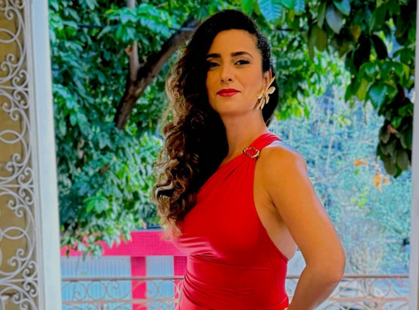 Cantora Aline Calixto usa vestido vermelho e está de lado, olhando para a câmera. Ela comanda roda de samba em BH