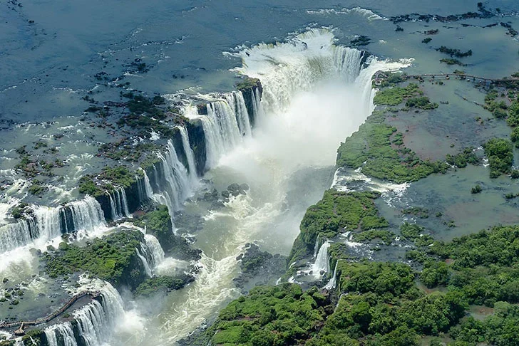 Maior catarata (em volume): Cataratas do Iguaçu  - Localizada entre o Parque Nacional do Iguaçu, Paraná (Brasil) e o Parque Nacional Iguazú em Misiones (Argentina), na fronteira. Tem 275 quedas de água ao longo de 2,7 km do rio Iguaçu. Algumas quedas individuais têm até 82, de altura (a maioria tem 64m). -Enaldo Valadares wikimedia commons