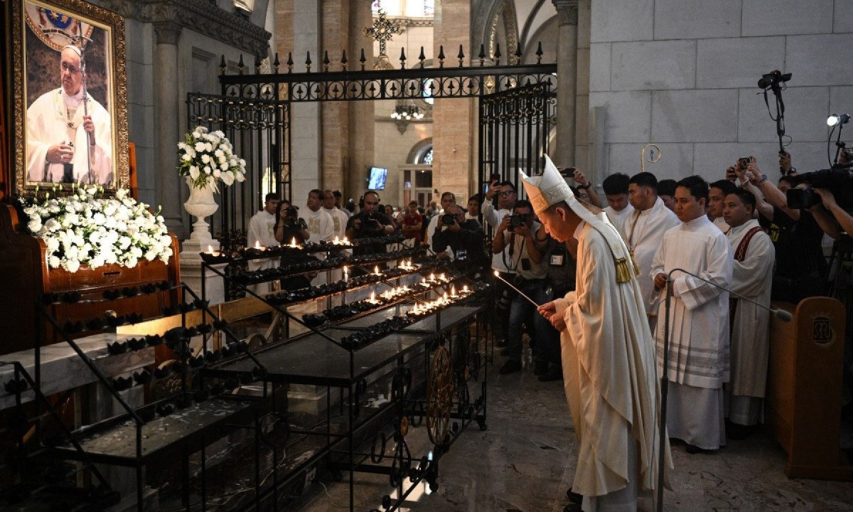 Cardeal José Advincula acende vela e oferece orações diante de retrato do Papa Francisco, antes da missa de réquiem na Catedral de Manila, nas Filipinas, em 22 de abril de 2025 -  (crédito: TED ALJIBE / AFP)