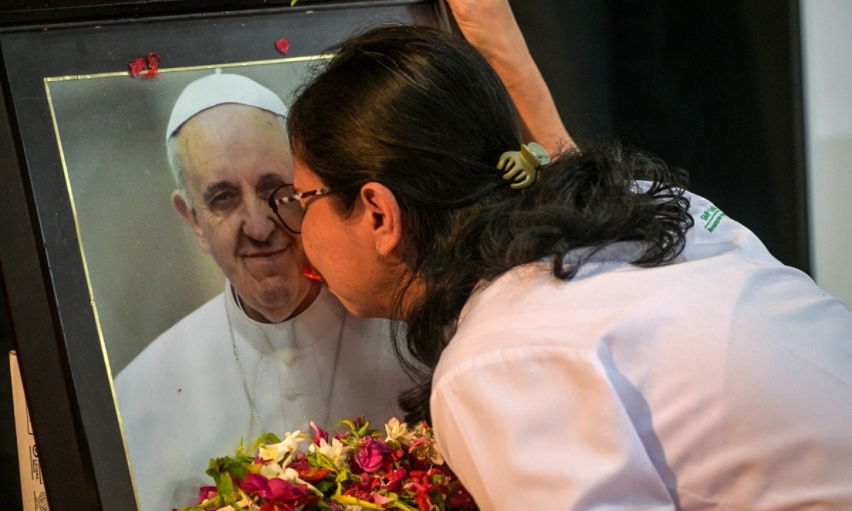 Professora beija retrato do Papa Francisco em exposição em escola na Indonésia; papa morreu nesse dia 21/04/2025
       -  (crédito: Juni KRISWANTO / AFP)