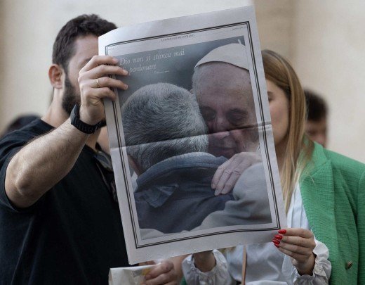  People hold the Osservatore Romano newspaper with a picture of Pope Francis at St Peter's Square in the Vatican, a day prior to the Pope's funeral, on April 25, 2025. The Vatican on April 25, 2025, said 150,000 people have already paid their respects to Pope Francis, whose body is lying in state in St Peter's Basilica ahead of his funeral. (Photo by MARCO BERTORELLO / AFP)
      