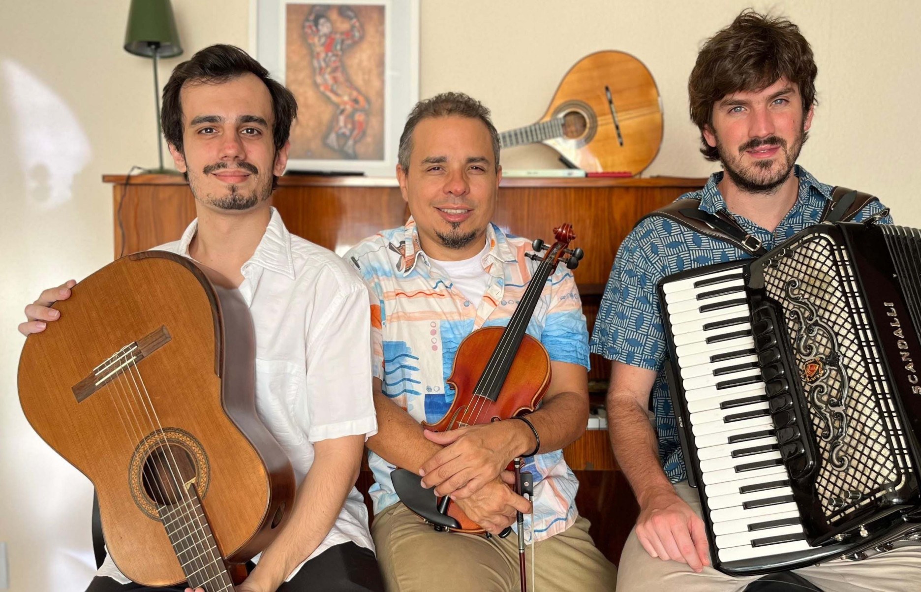 Três integrantes do Grupo Chorando em Cordas seguram instrumentos musicais e olham para a câmera