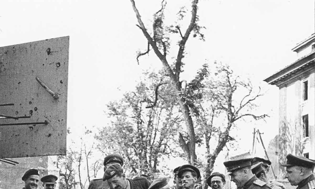 Em Berlim, Winston Churchill se senta em uma das cadeiras danificadas do bunker de Hitler, rodeado por soldados britânicos e soviéticos Em Berlim, Winston Churchill se senta em uma das cadeiras danificadas do bunker de Hitler, rodeado por soldados britânicos e soviéticos