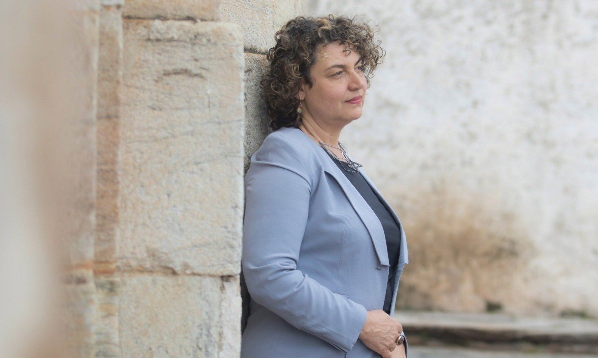 Escritora Guiomar de Grammont está de lado, recostada em pilastra de construção antiga da cidade mineira de Ouro Preto