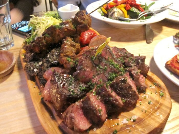 A carne é preparada sobre uma grelha que não deixa a gordura escorrer para o carvão. Também usa-se lenha. As preferidas são maminha, contra-filé e costela.  Acompanham legumes, principalmente batata, e salada. -Divulgação meuguiaturistico