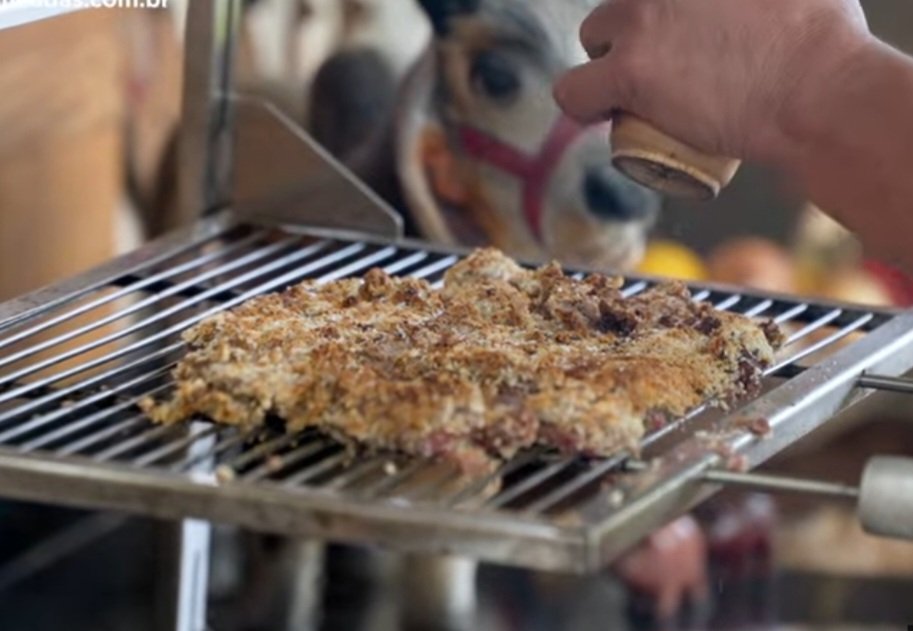 No vídeo, o churrasqueiro usou filé mignon, mas dá pra usar fraldinha, contrafilé e até patinho. Um pedaço de carne deve ser mergulhado em ovos para garantir que a farinha de rosca grude de maneira uniforme. Cubra a carne com a farinha e bote 60 cm acima do fogo para não queimar. -Reprodução YouTube Canal Churrasqueadas,