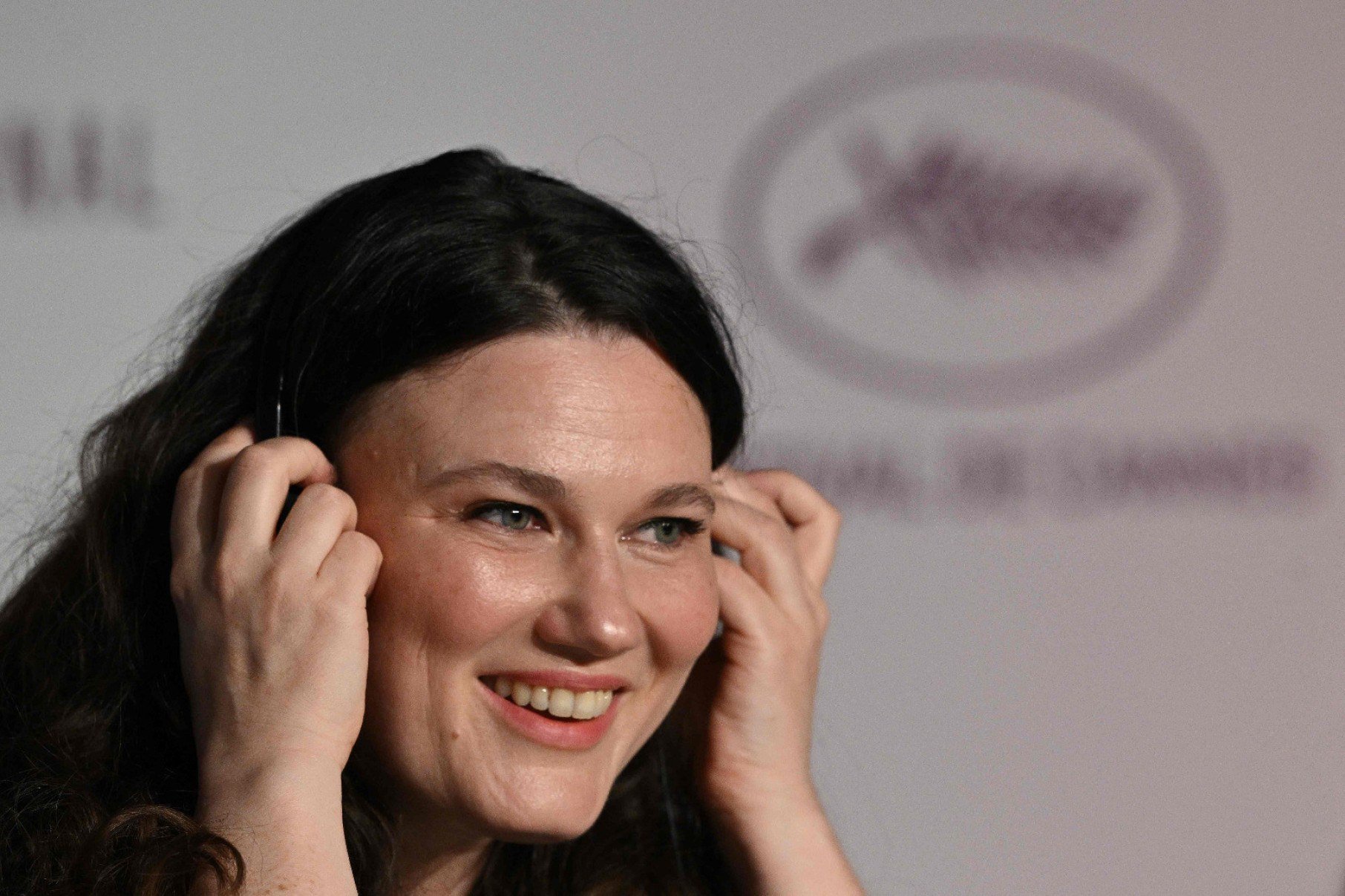 Diretora alemã Mascha Schilinski põe fones de ouvido e sorri durante entrevista no Festival de Cannes