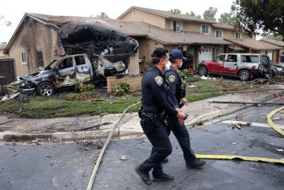 Policiais fazem buscas no local da queda do avião em uma rua residencial de San Diego, na Califórnia
      -  (crédito: Sandy Huffaker / AFP)