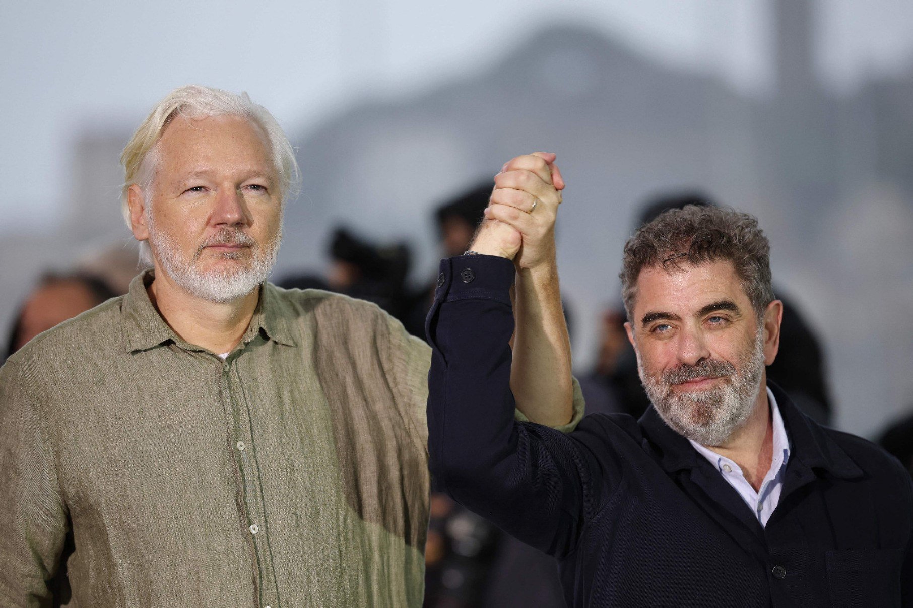  Julian Assange levanta o braço do cineasta Eugene Jarecki, diretor do filme 'The six billion dolar man', no Festival de Cannes