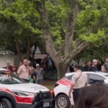 Um registro publicado no X mostra diversas pessoas gritando 'racista' ao redor dos carros da polícia -  (crédito: X/Reprodução)