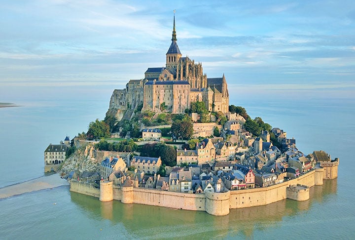 MONTE SAINT-MICHEL - Ã? uma ilha rochosa, cerca por muralhas, na regiÃ£o da Normandia, na FranÃ§a. No decorrer da Guerra dos Cem anos foi uma defesa impenetrÃ¡vel, pois todas as tentativas inglesas de tomÃ¡-la foram fracassadas. Assim, virou um sÃ­mbolo do nacionalismo francÃªs e foi utilizada como prisÃ£o durante a RevoluÃ§Ã£o sa.