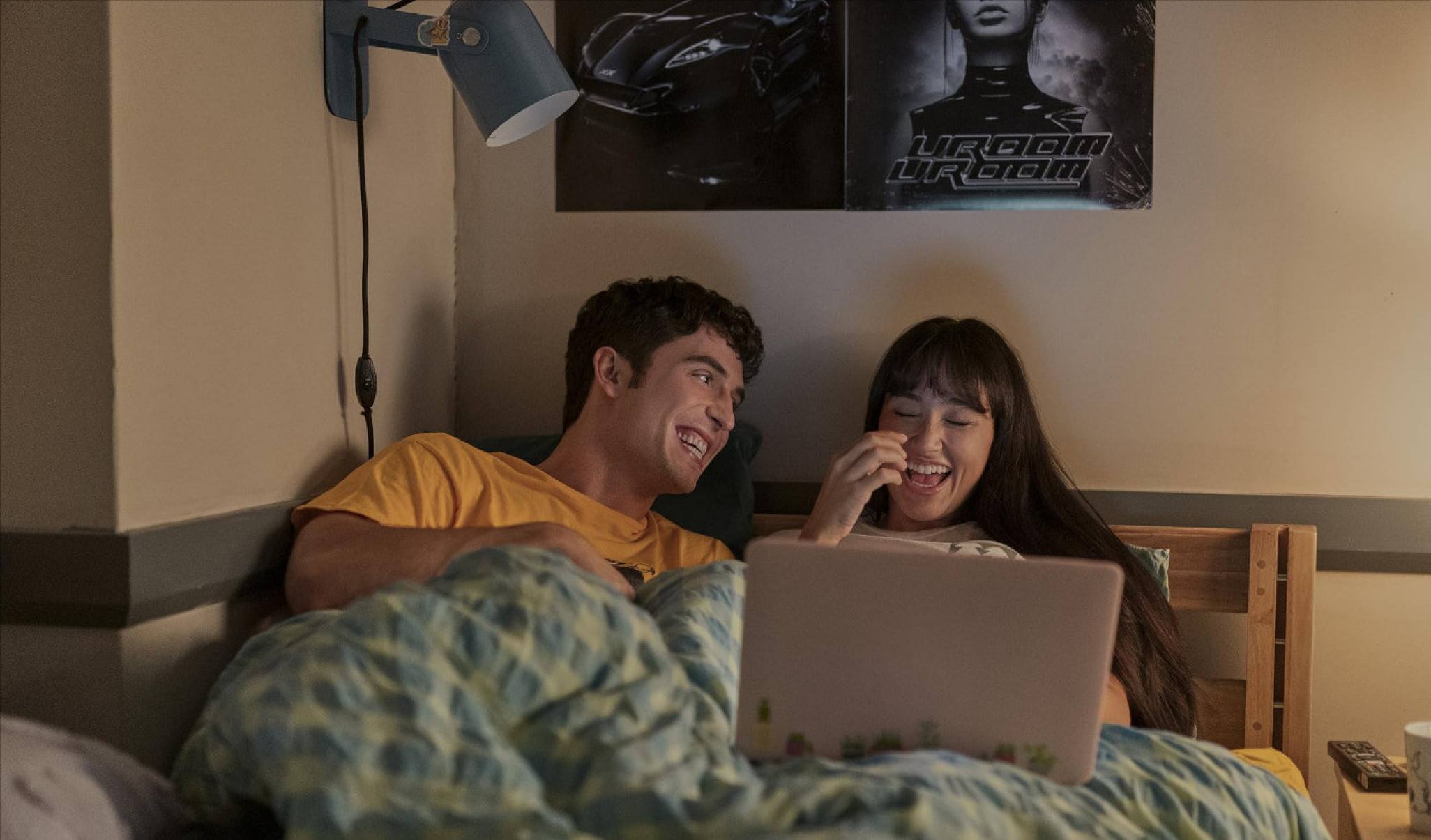 Atores Benito Skinner) e Wally Baram estão na cama, olhando computador, em cena da série Muito esforçado