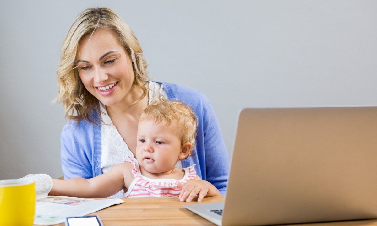 
Mãe segura bebê enquanto trabalha em home-office -  (crédito: Freepik)