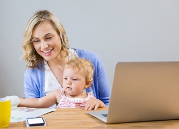 
Mãe segura bebê enquanto trabalha em home-office -  (crédito: Freepik)