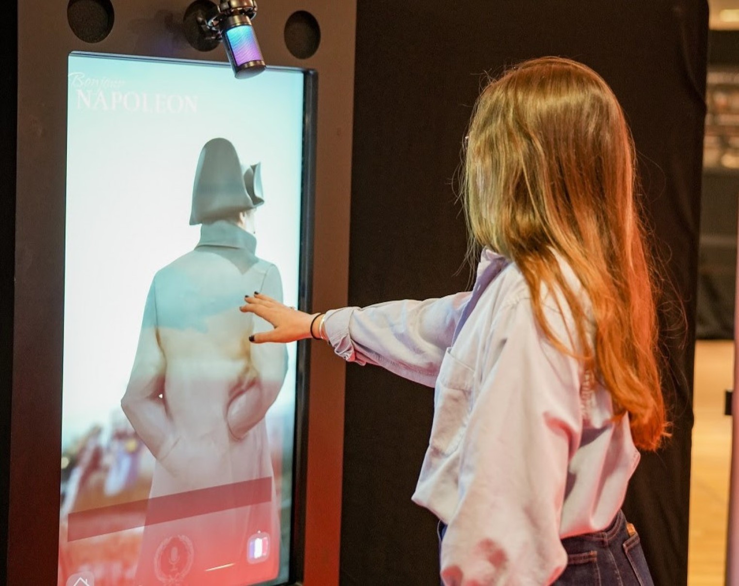 Jovem toca uma tela interativa na exposição sobre Napoleão Bonaparte em cartaz em Belo Horizonte