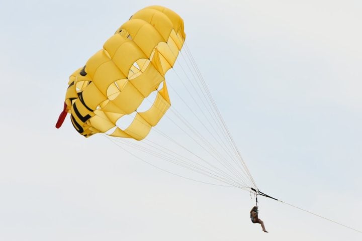 Conforme o barco acelera, o parasail é inflado pelo vento, elevando o participante a alturas que podem variar entre 30 e 150 metros, dependendo das condições climáticas e do comprimento da corda.-Pexels/Alan Kotok