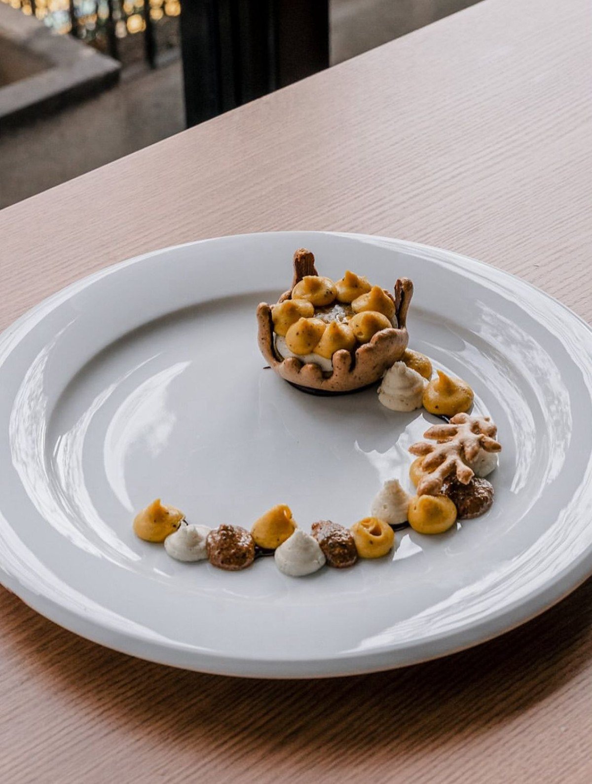 Tartelette Rústica com tuile de castanha de pequi com mascavo, mousse de chocolate branco, ganache monté de maracujás doce e azedo, praliné de castanha de pequi e gel de maracujá doce