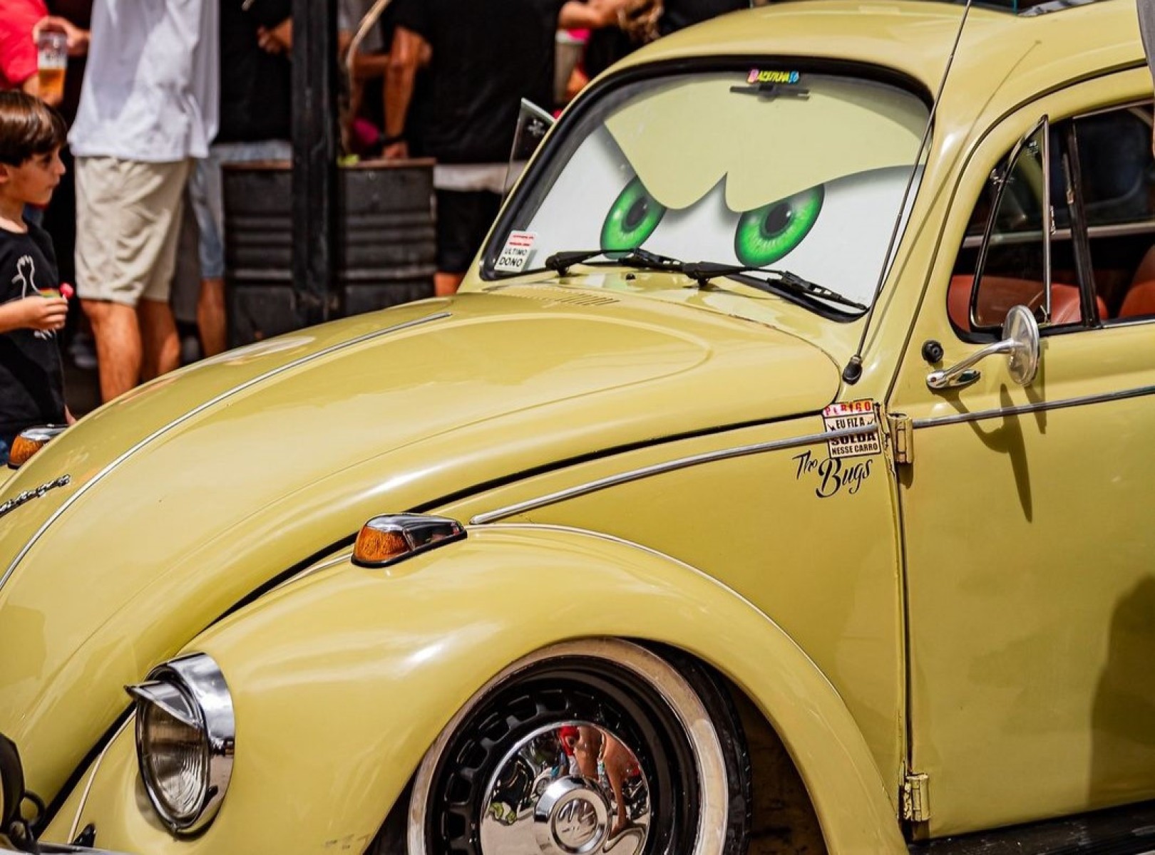 Foto de fusca amarelo antigo, com desenhos de dois olhos no para-brisa 