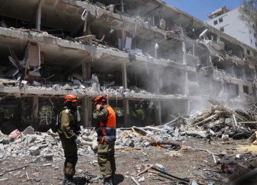 Forças de segurança israelenses observam enquanto uma escavadeira limpa os escombros de um prédio destruído no local de um ataque iraniano que atingiu um bairro residencial na área de Ramat Aviv, em Tel Aviv. Pelo menos 16 pessoas ficaram feridas e pelo menos um impacto foi relatado no centro de Israel depois que o Irã lançou duas ondas de mísseis no país após o bombardeio dos EUA em suas instalações nucleares, disseram serviços de resgate e relatórios -  (crédito: Jack GUEZ / AFP)