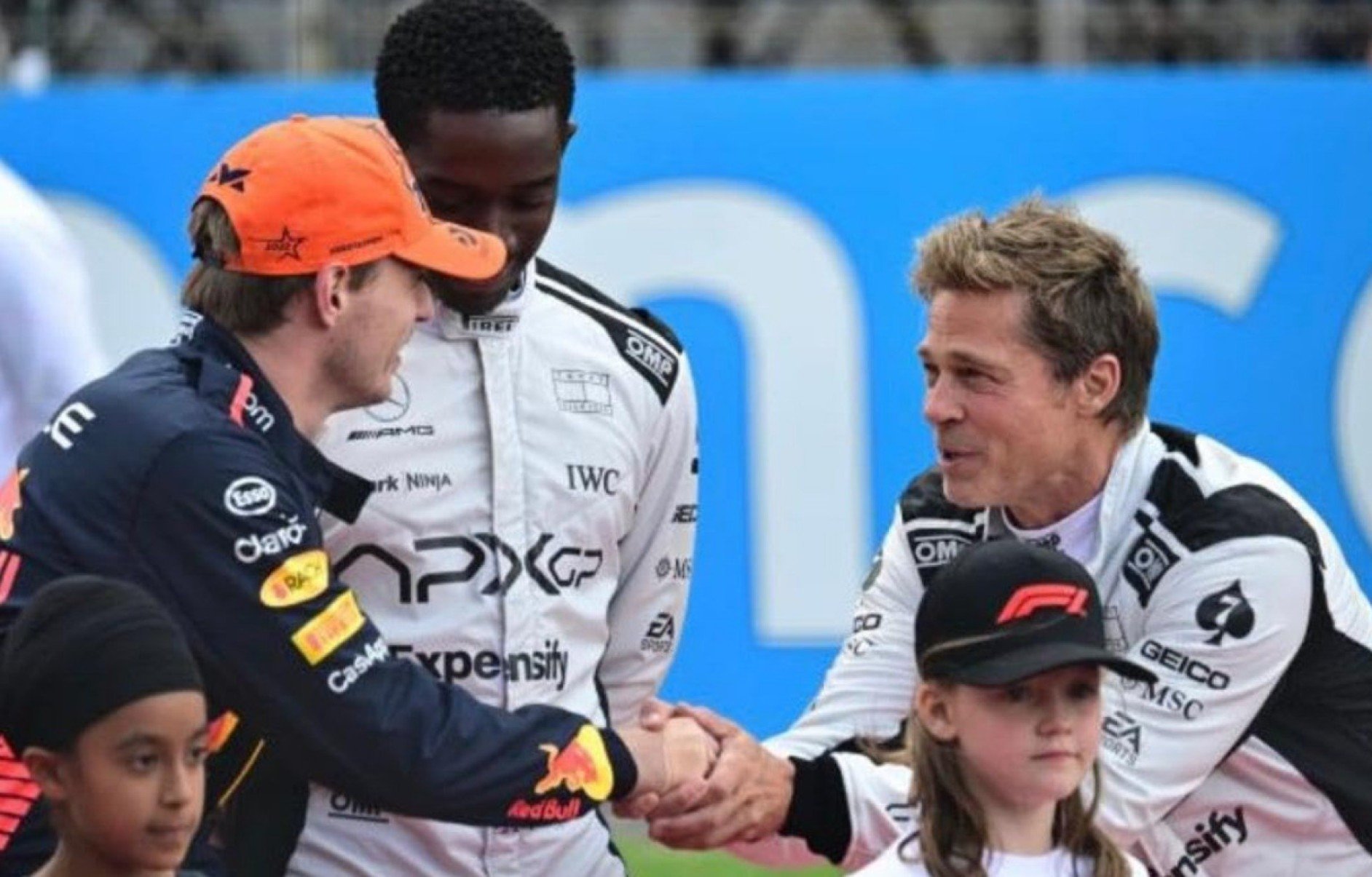 O piloto holandês Max Verstappen cumprimenta Brad Pitt, que interpreta Sonny Hayes no filme F!. Atrás deles está o ator Damson Idris, no papel do jovem piloto Joshua Pearce