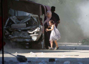 Mulher palestina tenta proteger sua filha durante ataque de Israel na área central de Gaza -  (crédito: Eyad BABA/AFP)