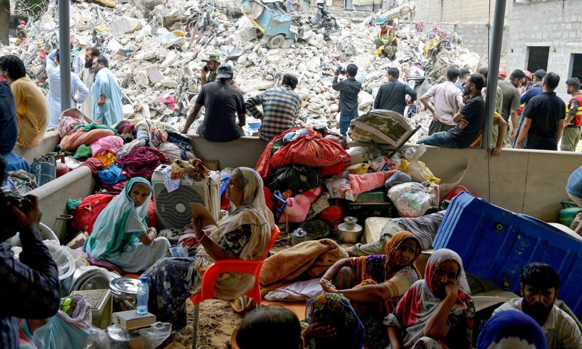  Famílias esperam pelo resgate de corpos em meio aos escombros de um prédio que desabou em Karachi, no Paquistão -  (crédito:  AFP)