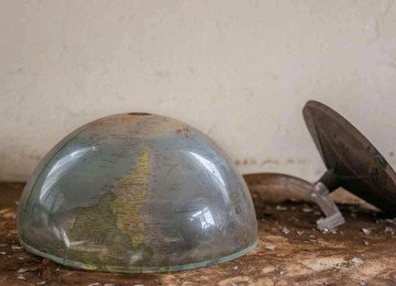 Nos escombros de uma sala de aula, o globo terrestre partido ao meio caído ao chão tem a imagem do mapa do Brasil de cabeça para baixo -  (crédito: Isis Medeiros/Divulgação)
