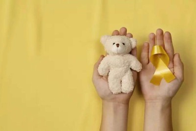 Fundo amarelo,  um ursinho e o laço,  símbolos da campanha de conscientização para a prevenção do câncer infantil -  (crédito: Freepik)