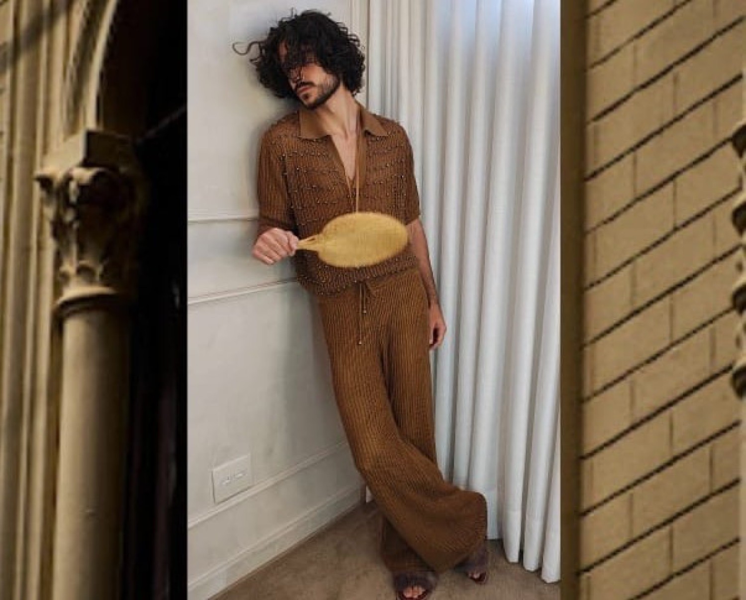 Modelo Gabriel Araújo está recostado na parede e veste roupa da grife Isa Paes