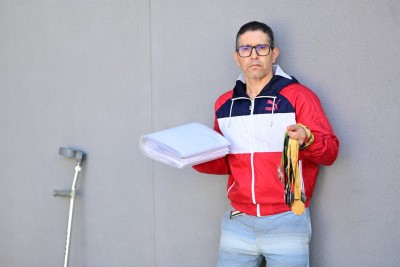 Em uma mão, ele diz carregar sua vitórias, que são suas medalhas e o livro escrito por ele e, na outra, o calhamaço de documentos médicos, que seriam suas derrotas -  (crédito: Leandro Couri/EM/DA Press)