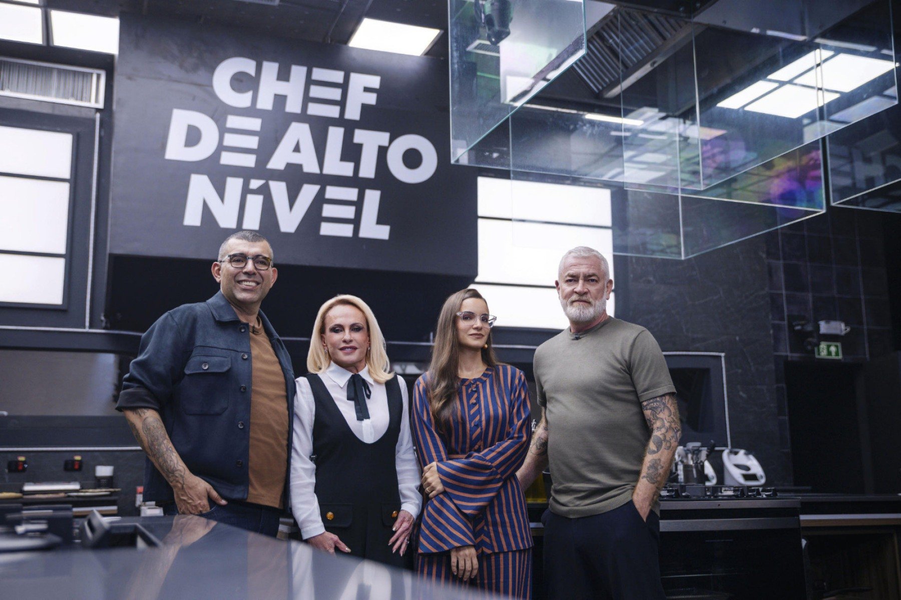 Jefferson Rueda, Ana Maria Braga, Renata Vanzetto e Alex Atala sorriem para a câmera. Os quatro estão lado a lado na imensa cozinha que serve como cenário para o programa Chef de alto nível